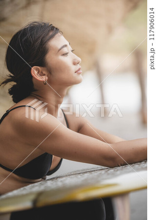 岩場でサーフボードを持っている若い女性 岩場でサーフボードを持っている若い女性 117906014