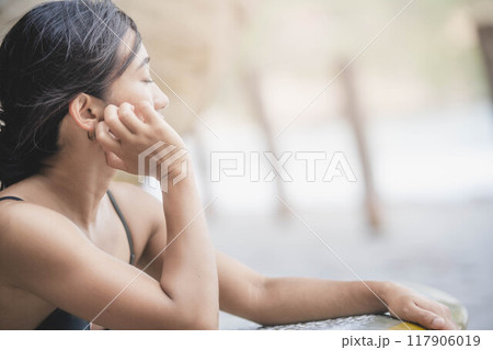 岩場でサーフボードを持っている若い女性 117906019