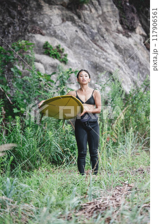 サーフボードを持って自然の中にいる若い女性 117906561