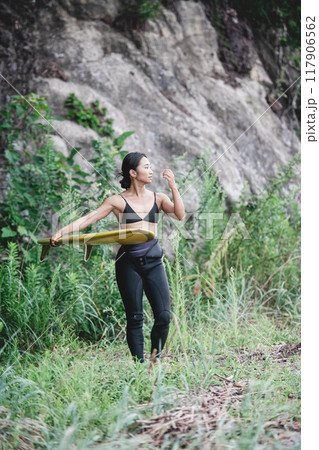 サーフボードを持って自然の中にいる若い女性 117906562
