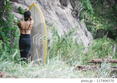 サーフボードを持って自然の中にいる若い女性 117906570