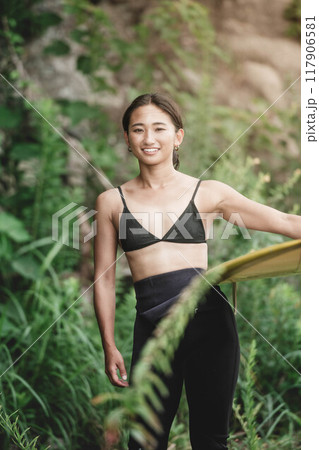 サーフボードを持って自然の中にいる若い女性 117906581