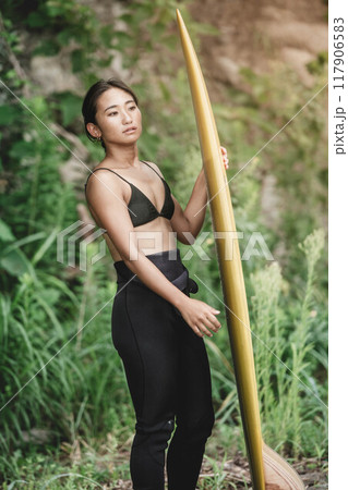 サーフボードを持って自然の中にいる若い女性 サーフボードを持って自然の中にいる若い女性 117906583