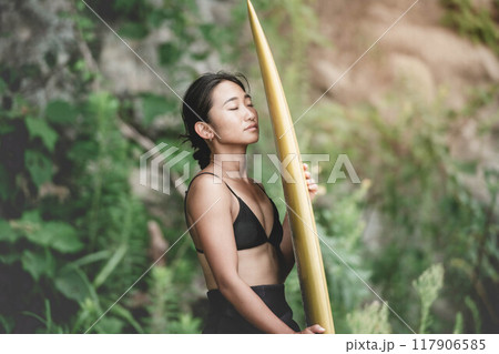 サーフボードを持って自然の中にいる若い女性 117906585
