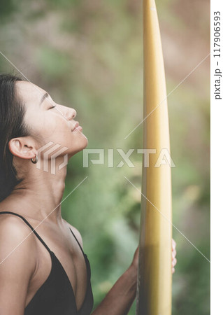 サーフボードを持って自然の中にいる若い女性 117906593