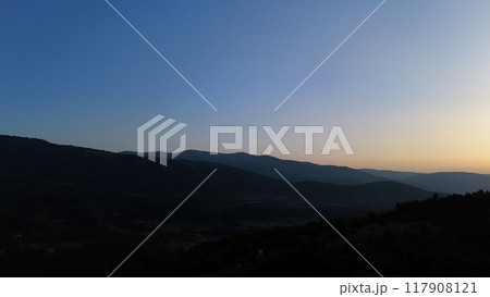 A tranquil twilight over rolling hills creates a serene landscape in the fading light of sunset 117908121