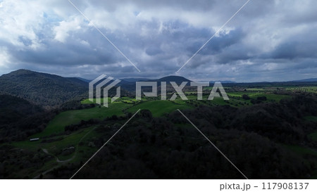 Vast green valleys and rolling hills under a dramatic cloudy sky during late afternoon in a serene countryside landscape Vast green valleys and rolling hills under a dramatic cloudy sky during late afternoon in a serene countryside landscape 117908137