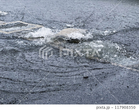 大雨で側溝から溢れる雨水 117908350