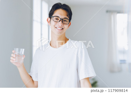 コップで水を飲む若い男性 117909814