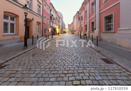 A deserted narrow cobblestone street in the center of Poznan at dawn. 117910559