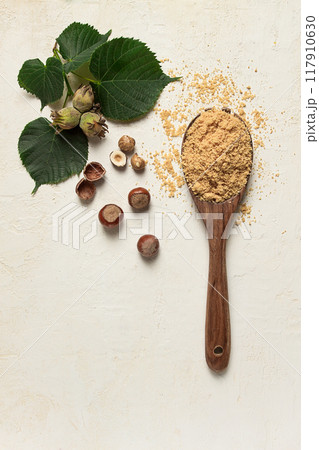 wooden spoon with hazelnut flour, top view, no people, on a white table 117910630
