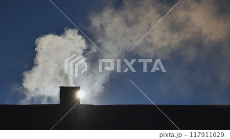 Silhouette of smoke against blue sky from the chimney of a village house. Silhouette of smoke against blue sky from the chimney of a village house. 117911029