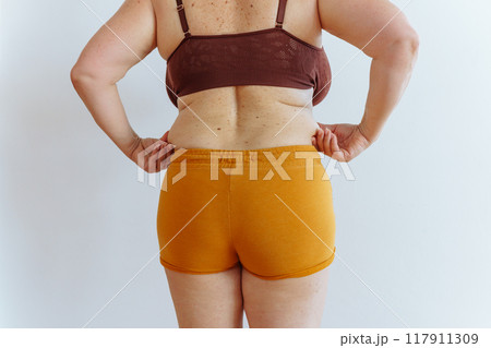 unrecognizable woman showing fat belly with saggy skin 117911309