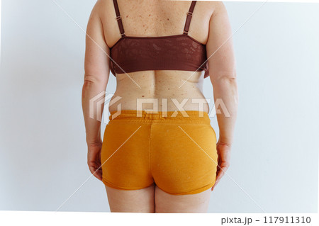unrecognizable woman showing fat belly with saggy skin 117911310