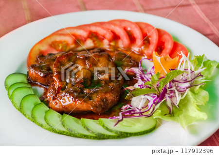 Traditional asian cuisine - fried pork in sweet and sour sauce, fresh vegetables, sesame and mint leaves. Vietnamese food at cafe. Traditional asian cuisine - fried pork in sweet and sour sauce, fresh vegetables, sesame and mint leaves. Vietnamese food at cafe. 117912396
