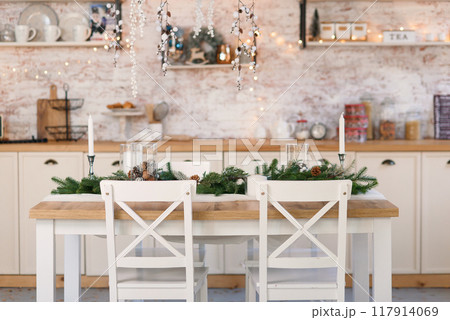 Living room decorated for Christmas with with wooden table, Christmas tree branches and lights. Living room decorated for Christmas with with wooden table, Christmas tree branches and lights. 117914069