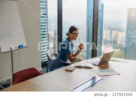 A professional woman engaging in video conferencing within a modern office environment A professional woman engaging in video conferencing within a modern office environment 117915302