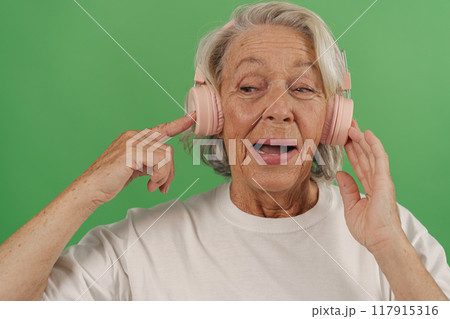 An Elderly Woman Joyfully Enjoying Her Favorite Music While Comfortably Wearing Headphones An Elderly Woman Joyfully Enjoying Her Favorite Music While Comfortably Wearing Headphones 117915316