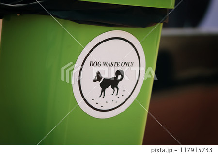 Waste management, green plastic bin featuring a white sign proclaiming its exclusive purpose for dog waste disposal, emphasizing environmental responsibility and the cleanliness of canine excrement. 117915733