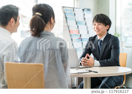 ショールーム・商談スペースで接客する若いアジア人ビジネスマンと客の夫婦 ショールーム・商談スペースで接客する若いアジア人ビジネスマンと客の夫婦 117916227
