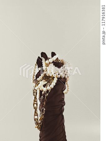 Female hand in a black glove is holding a lot of gold and pearl jewelry. Minimalist concept creative photography, vintage retouch. Female hand in a black glove is holding a lot of gold and pearl jewelry. Minimalist concept creative photography, vintage retouch. 117916381