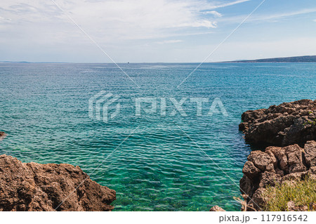 Krk Croatia 26.06.24 Stone beach with blue sea water 117916542