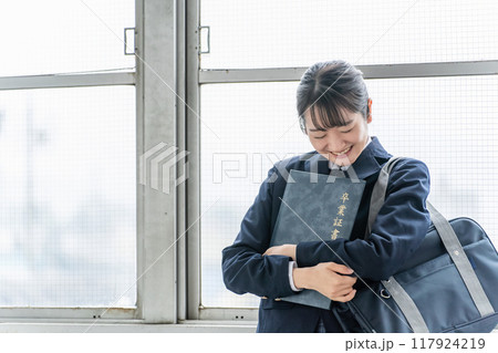 学校の教室で卒業証書・証書ファイルを持つ笑顔の高校生・中学生・女子高生（卒業式・制服・学生服） 117924219