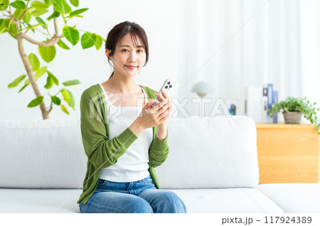 部屋でスマホを操作する若い女性 部屋でスマホを操作する若い女性 117924389