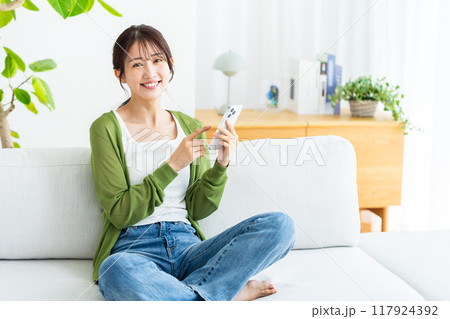 部屋でスマホを操作する若い女性 部屋でスマホを操作する若い女性 117924392