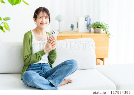 部屋でスマホを操作する若い女性 部屋でスマホを操作する若い女性 117924393