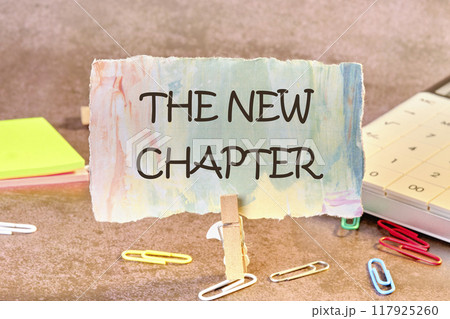 Conceptual the new chapter symbol. Copy space. The new chapter words written on a piece of paper in a clothespin Conceptual the new chapter symbol. Copy space. The new chapter words written on a piece of paper in a clothespin 117925260