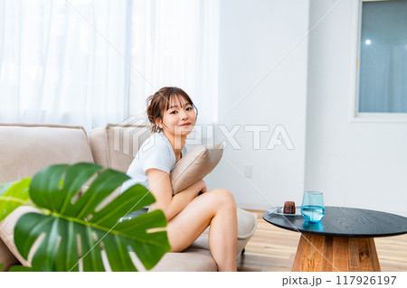 ソファでくつろぐ部屋着の女性/休日の朝/リラックス ソファでくつろぐ部屋着の女性/休日の朝/リラックス 117926197