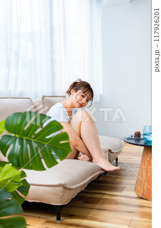 ソファでくつろぐ部屋着の女性/休日の朝/リラックス 117926201