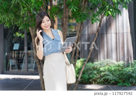 オフィス街でタブレット端末を持つビジネスウーマン オフィス街でタブレット端末を持つビジネスウーマン 117927592