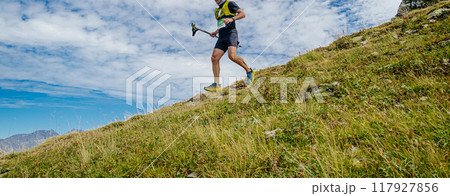 athlete with trekking poles in hand running steep descent in mountain marathon 117927856