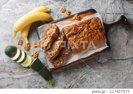 Vegan pasrty Banana Zucchini Bread with walnuts and dark chocolate closeup on the wooden board. Horizontal top view Vegan pasrty Banana Zucchini Bread with walnuts and dark chocolate closeup on the wooden board. Horizontal top view 117927875