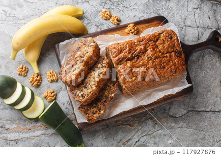 Freshly baked gluten free zucchini banana bread with walnuts and dark chocolate close-up on wooden board. Horizontal top view 117927876