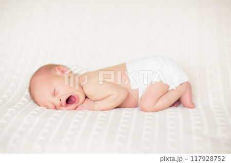 Little baby on white bed 117928752