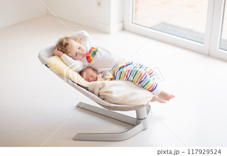 Child watching newborn baby in rocking chair 117929524