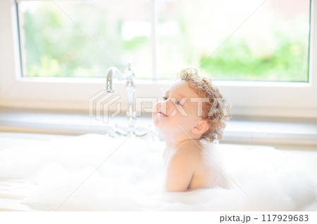 Baby taking bath in kitchen sink 117929683