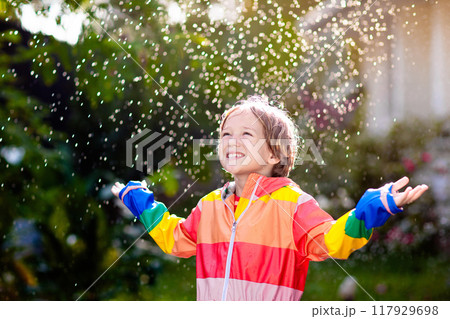 Child playing in autumn rain. Kid with umbrella. 117929698
