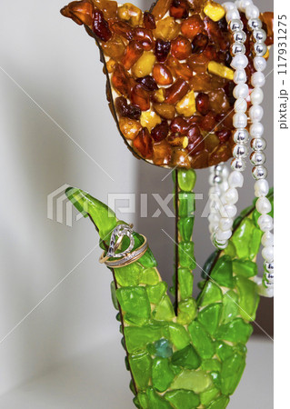 A beautiful necklace and a stunning ring are displayed on a vivid green flower A beautiful necklace and a stunning ring are displayed on a vivid green flower 117931275