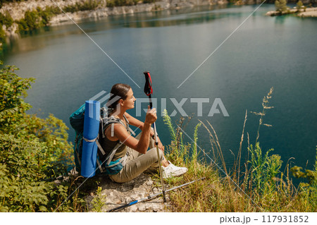 A Hiker Taking Delight in the Beautiful Scenic View by the Tranquil Water Body Nearby 117931852