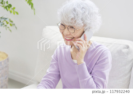 スマートフォンで電話するシニア女性 リビングルーム スマートフォンで電話するシニア女性 リビングルーム 117932240