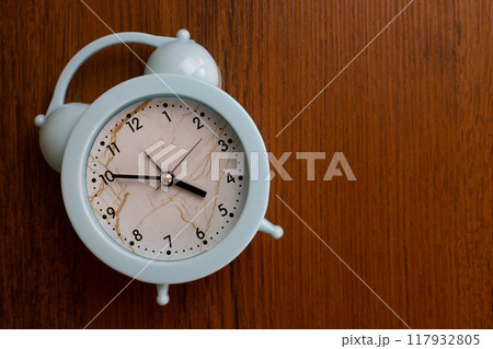 Home alarm clock lies on wooden background with space for text, domestic device to help wake up after healthy deep sleep 117932805