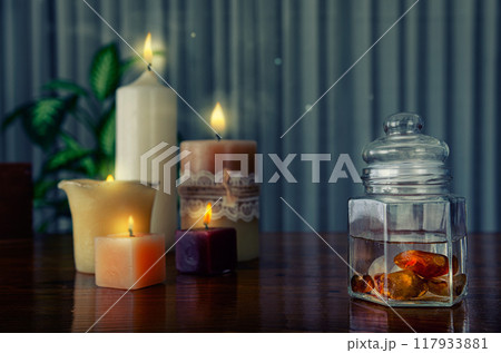 Soulful crystal elixir scene: Carnelian-infused water in glass container, surrounded by meditative candle glow. Soulful crystal elixir scene: Carnelian-infused water in glass container, surrounded by meditative candle glow. 117933881