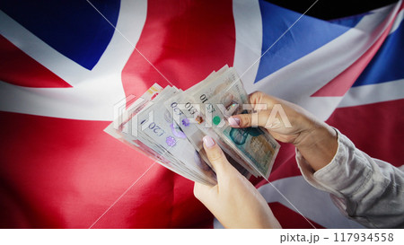 UK flag background. Woman counting GBP money pounds sterling. Credits, raising tariffs in Great 117934558