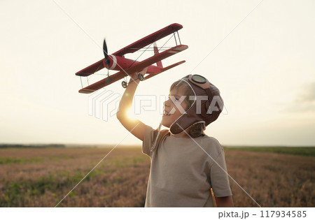 Smiling interested 5 years old child boy playing with wooden airplane, discovering future profession 117934585