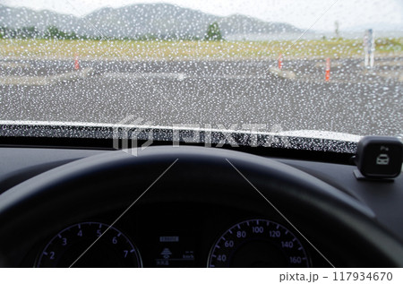 雨粒が付いたフロントガラスを運転席から見た構図 117934670