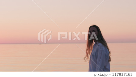 teenage girl standing on a beach at sunset teenage girl standing on a beach at sunset 117937163